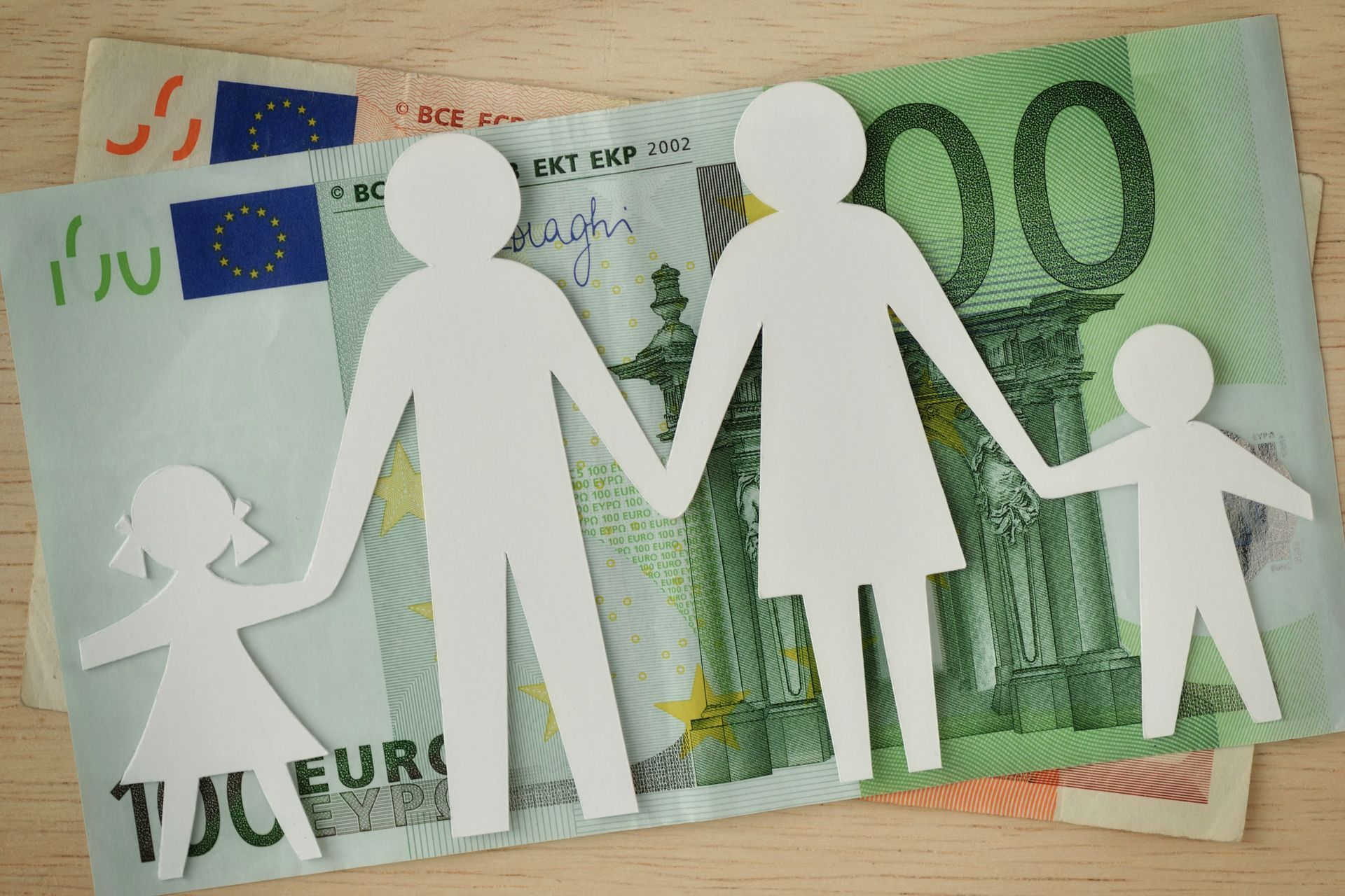 Ribambelle en papier d'une famille posée sur des billets de banque