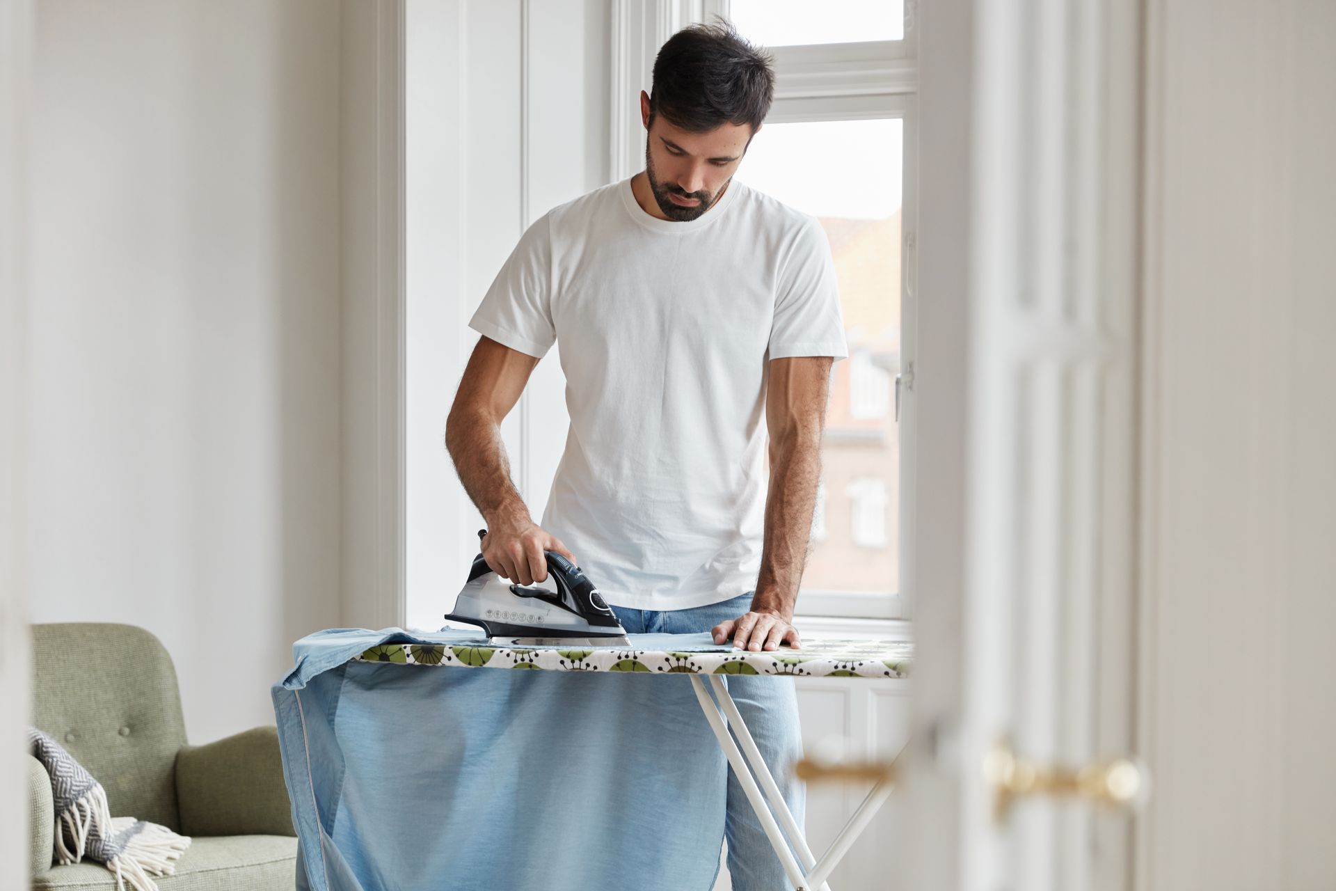 Homme repassant une chemise bleue
