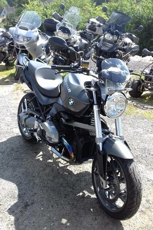 Moto grise de style Yamaha stationnée à l’extérieur, avec plusieurs motos derrière elle sur du gravier.
