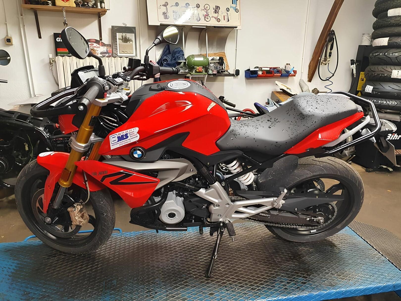 Moto sportive rouge stationnée dans un atelier, vue de côté sur une plateforme bleue en tôle à damier.
