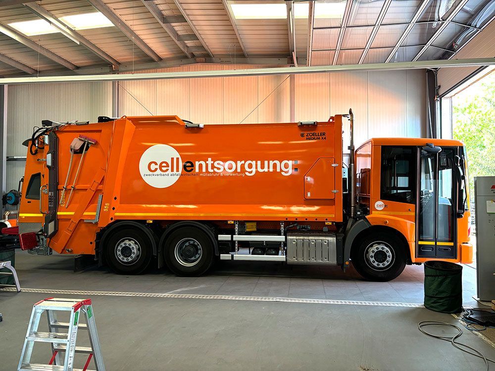 Ein orangefarbener Müllwagen steht in einer Garage.