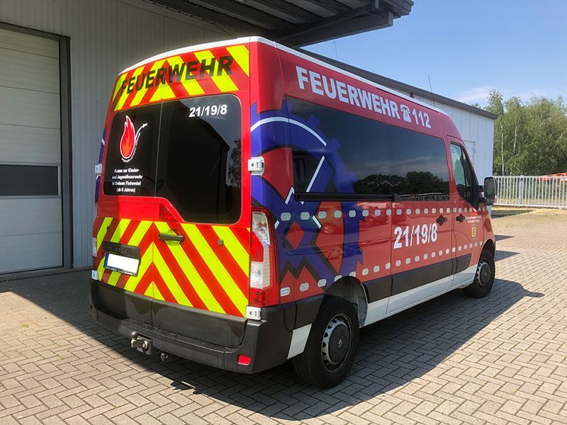 Ein rot-gelber Lieferwagen steht vor einem Gebäude.