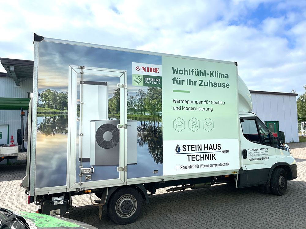 Ein weißer Lastwagen mit einer großen Werbung an der Seite steht vor einem Gebäude.