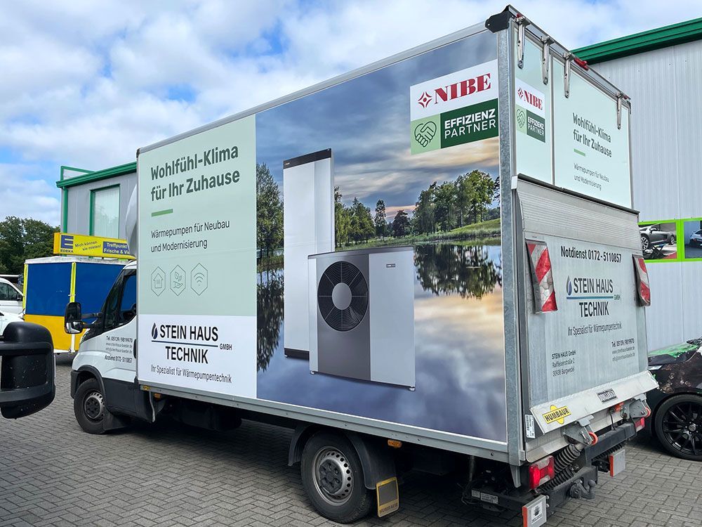 Vor einem Gebäude parkt ein Lastwagen mit dem Bild einer Heizung an der Seite.