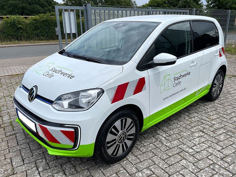 Ein weiß-grünes Auto parkt auf einer Ziegelsteinstraße.