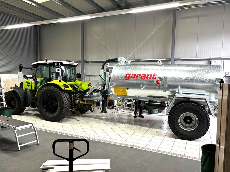 Ein Traktor steht in einer Garage neben einem großen Tank.