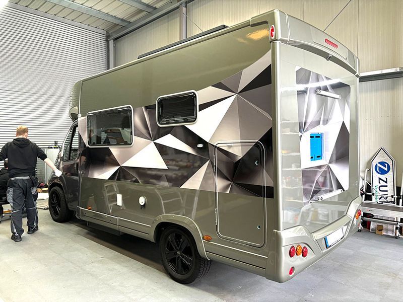 Ein Mann steht neben einem Wohnmobil in einer Garage.