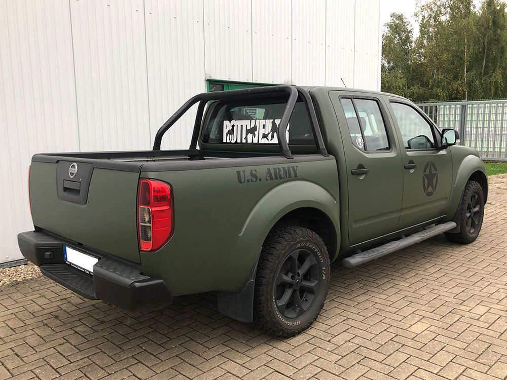 Ein grüner Nissan-Pickup-Truck steht auf einer gepflasterten Auffahrt vor einem Gebäude.