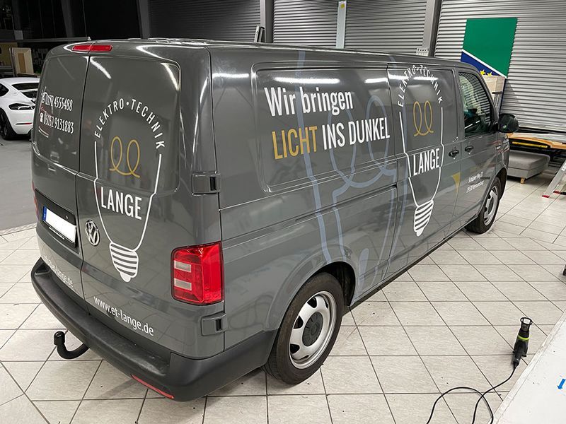 Ein grauer Lieferwagen mit einer Glühbirne an der Seite steht in einer Garage.