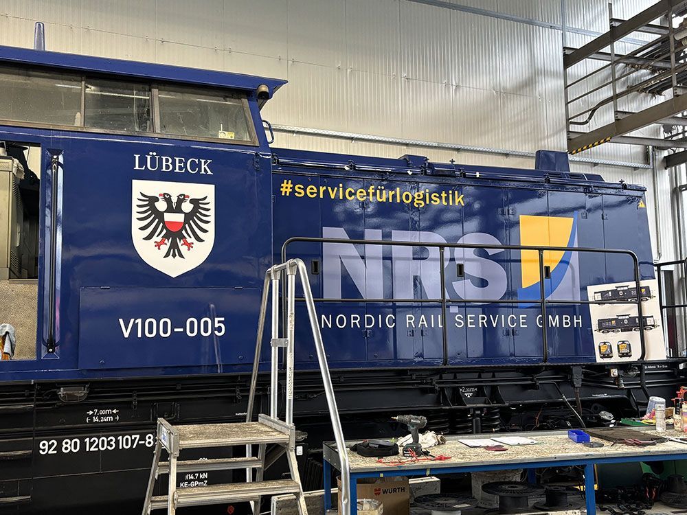 In einer Fabrik wird an einem blauen Zug gearbeitet.