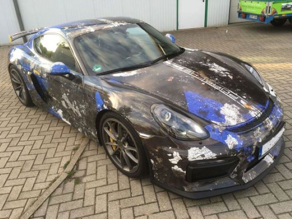 Ein schwarz - blauer Sportwagen steht auf einer gepflasterten Auffahrt.