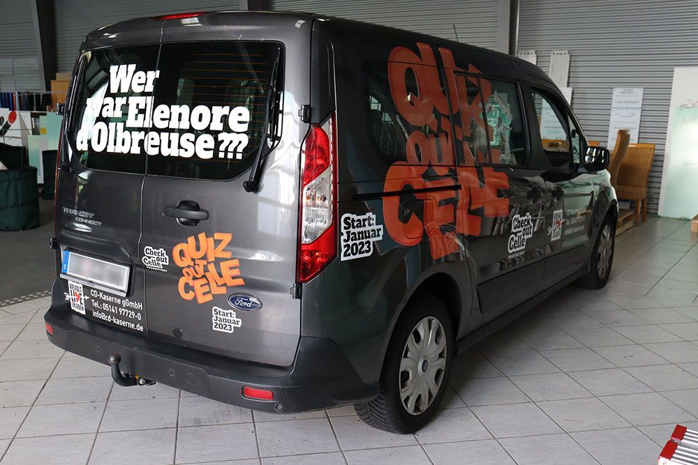 In einem Raum ist ein schwarzer Lieferwagen mit vielen Aufklebern geparkt.