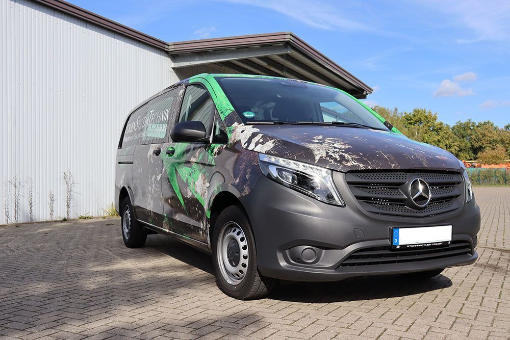 Ein Mercedes-Van parkt auf einem gepflasterten Gehweg vor einem Gebäude.