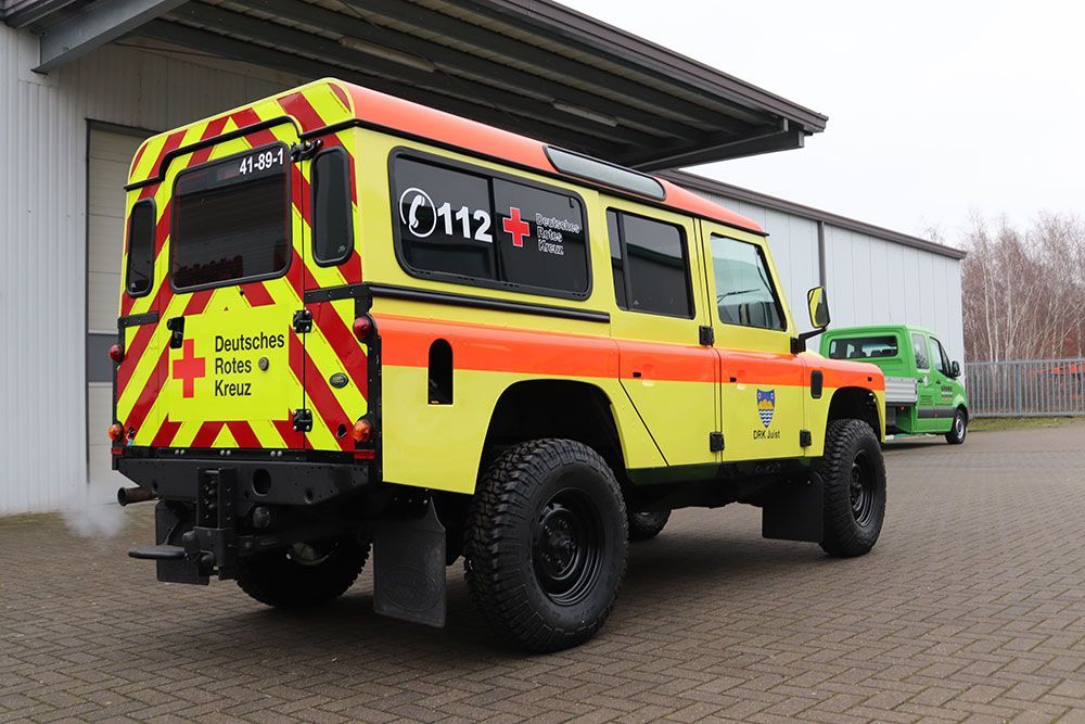 Vor einem Gebäude parkt ein gelb-roter Krankenwagen.