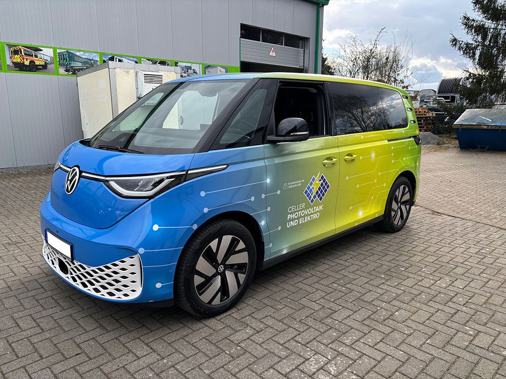 Ein blau - gelber Lieferwagen steht auf einer gepflasterten Auffahrt vor einem Gebäude.