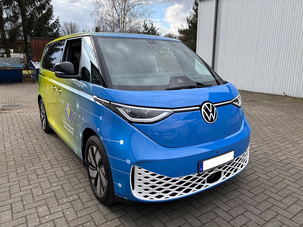 Ein blau - gelber Volkswagen Van steht auf einer gepflasterten Auffahrt.