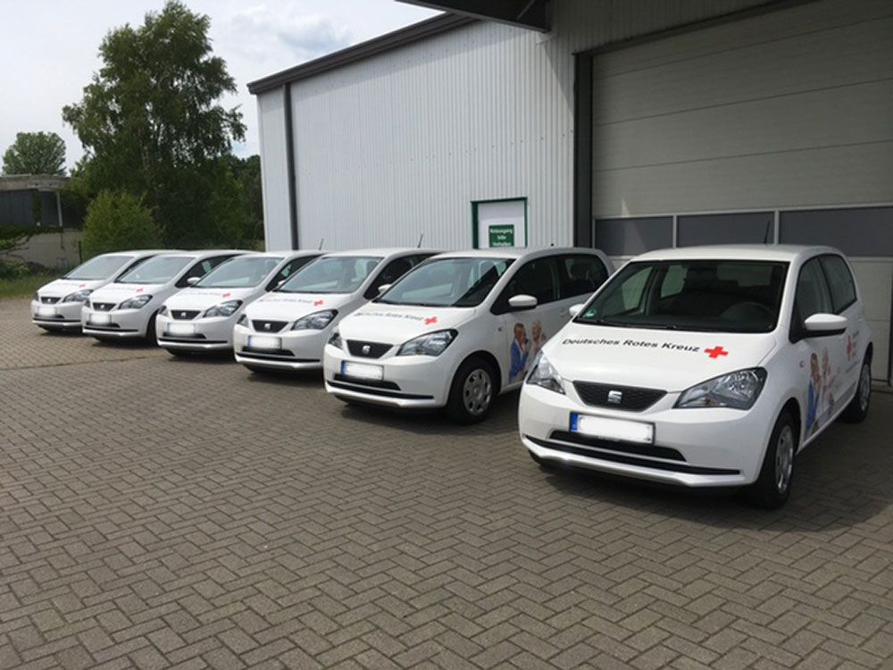 Eine Reihe weißer Autos, die vor einem Gebäude geparkt sind