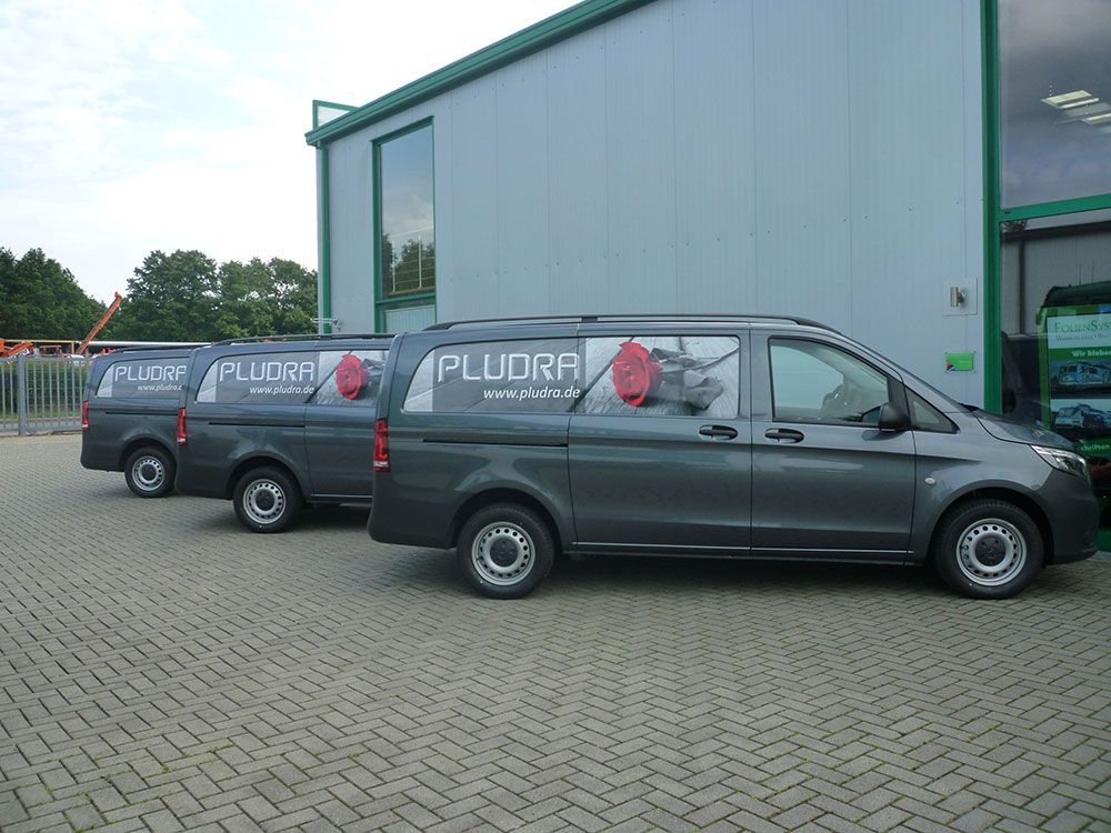 Drei Lieferwagen parken vor einem Gebäude.