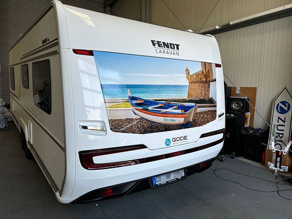In einer Garage steht ein weißer Wohnwagen mit dem Bild eines Bootes an der Seite.