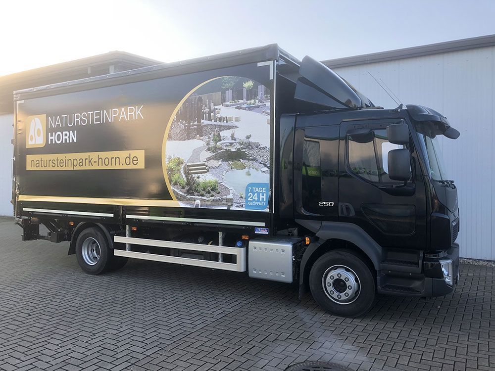 Vor einem Gebäude parkt ein schwarzer Lastwagen.