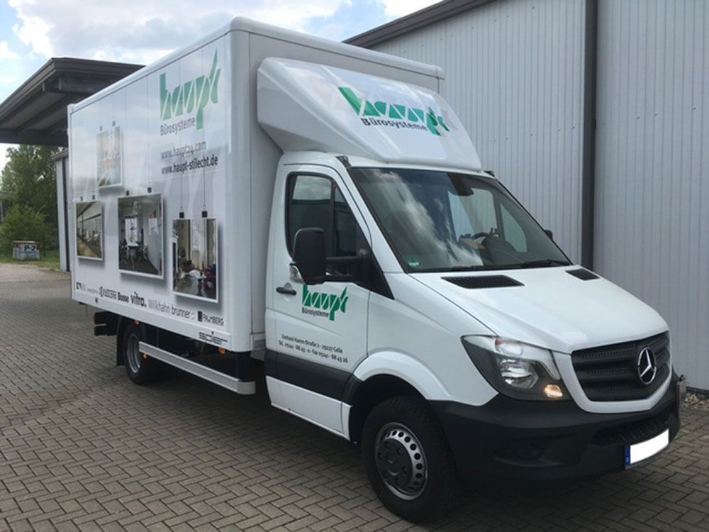 Ein weißer Lieferwagen steht vor einem Gebäude.