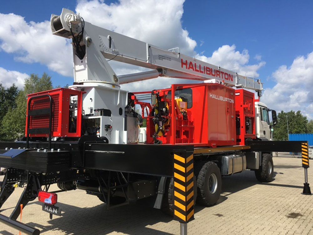 Ein rot-weißer Lastwagen mit einem daran befestigten Kran steht auf einem gepflasterten Gehweg.