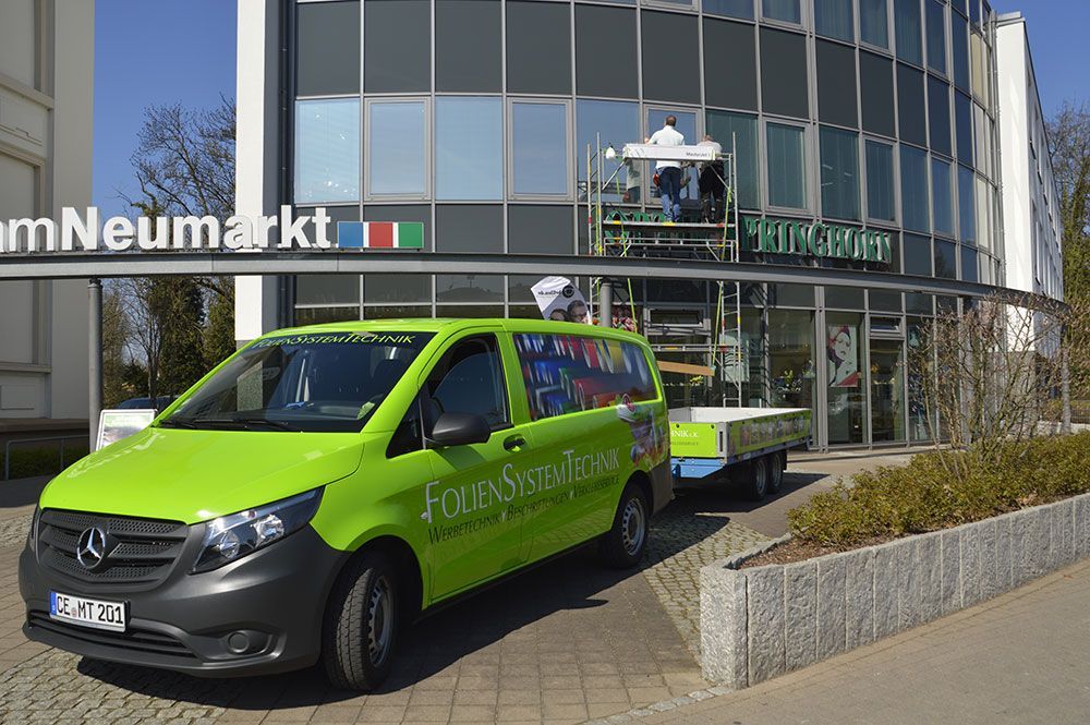 Ein grüner Lieferwagen steht vor einem Gebäude.