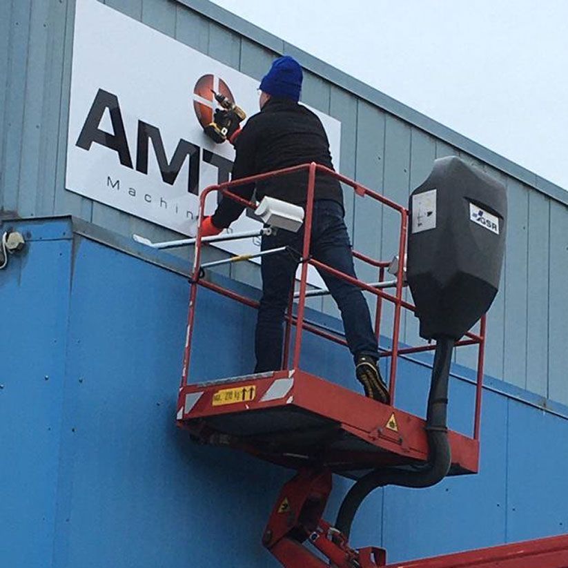 Ein Mann arbeitet an einem Schild mit der Aufschrift „amt“