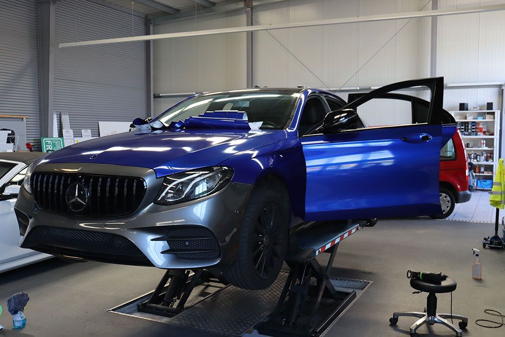 Ein blauer Mercedes Benz steht auf einer Hebebühne in einer Garage.