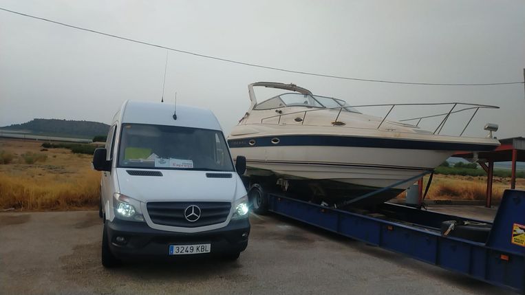 Una camioneta blanca está estacionada al lado de un barco en un remolque.