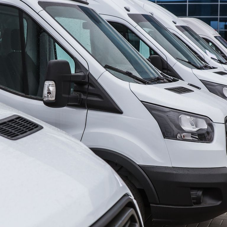 Una fila de furgonetas blancas están aparcadas una al lado de la otra