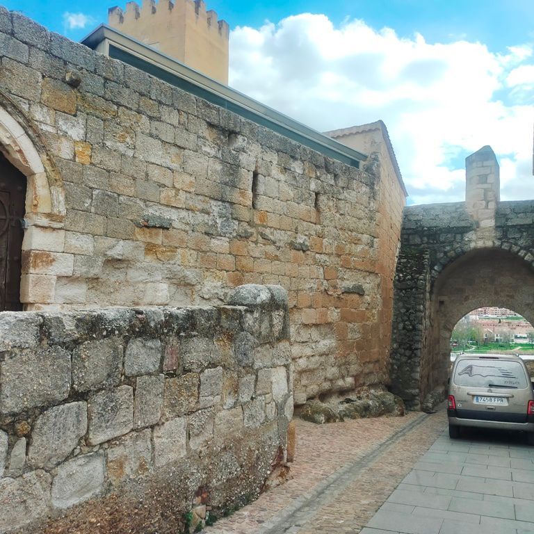 Un coche está aparcado delante de un muro de piedra.