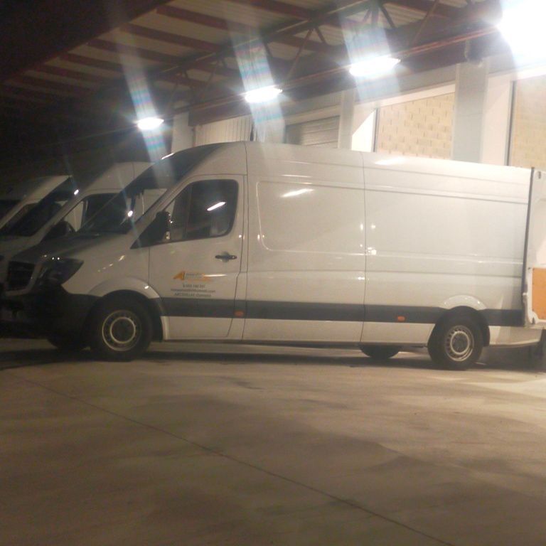 Una fila de furgonetas blancas están aparcadas en un garaje.