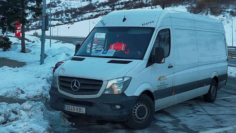 Una camioneta blanca está estacionada en la nieve en un estacionamiento.