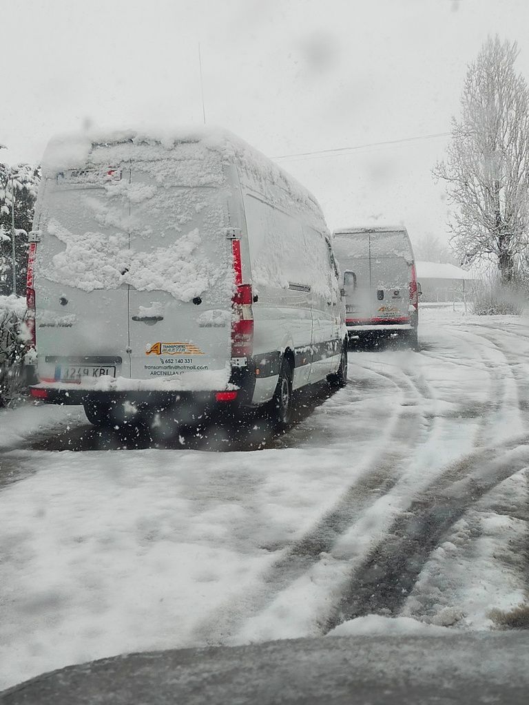Dos furgonetas están estacionadas en la nieve en una carretera nevada.