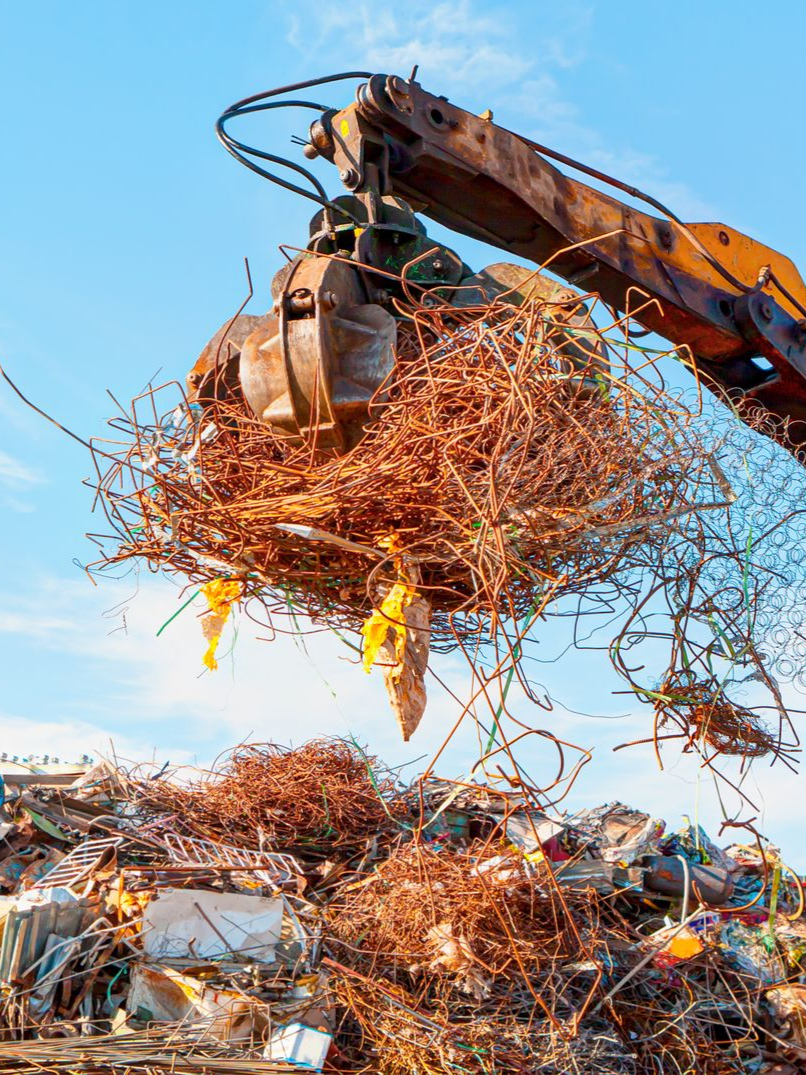 Une excavatrice soulève un tas de fils de cuivre emmêlés.