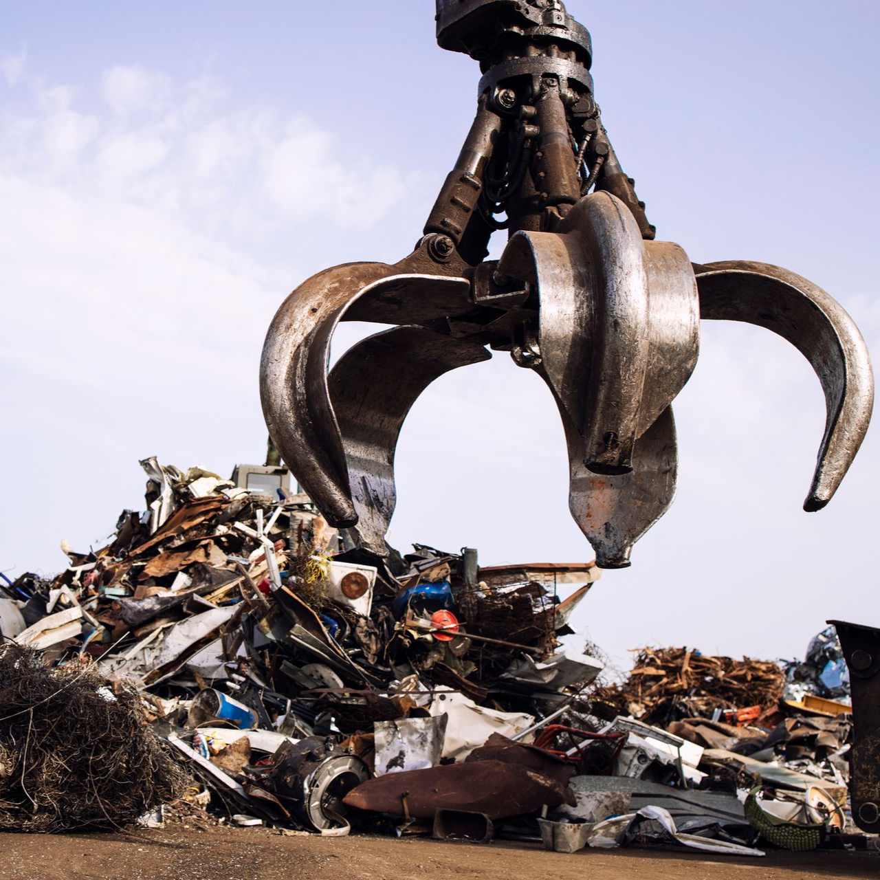 La griffe d'une machine lourde soulève des morceaux de métal.