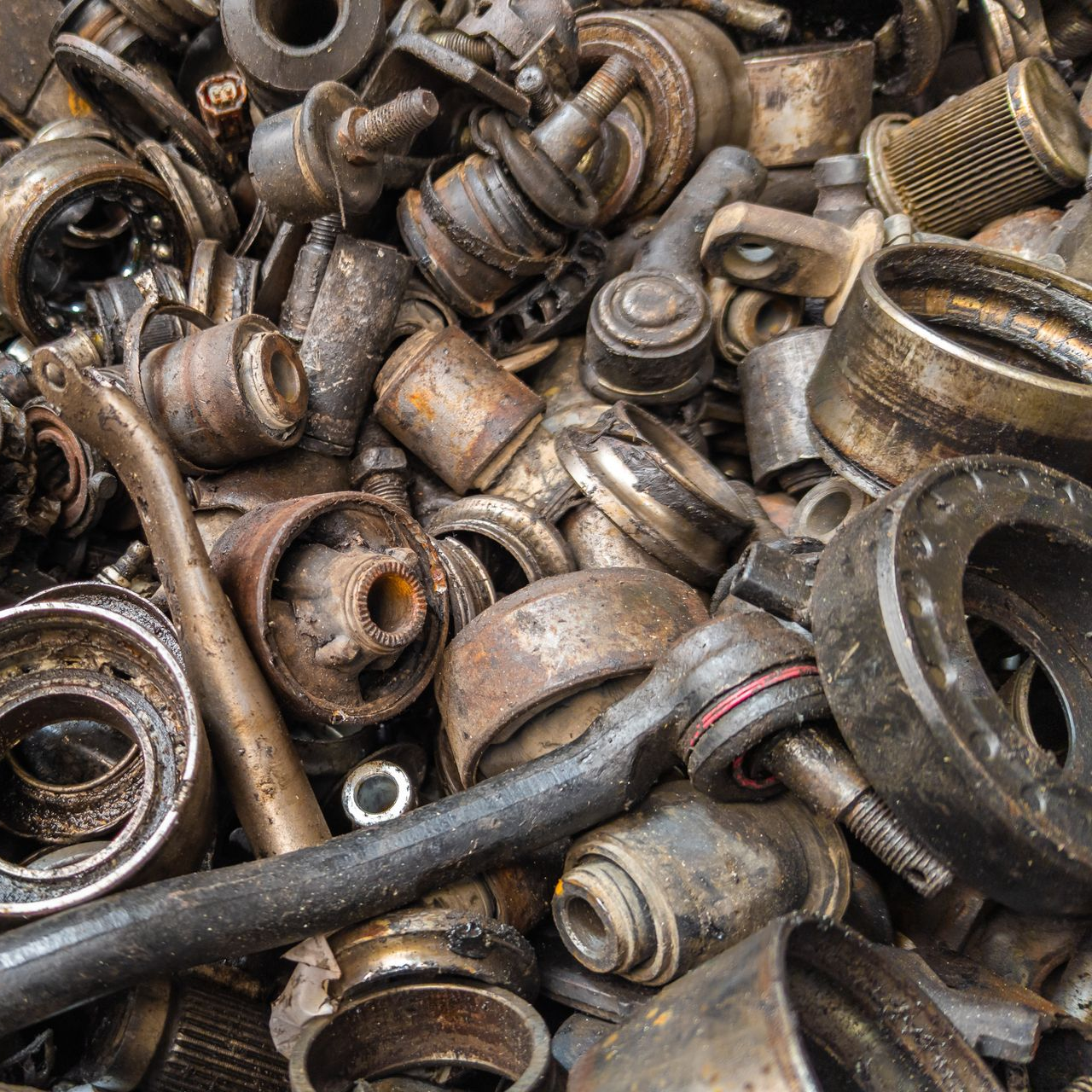 Un tas de pièces automobiles rouillées et usagées, comprenant des roulements, des biellettes de direction et des bagues.