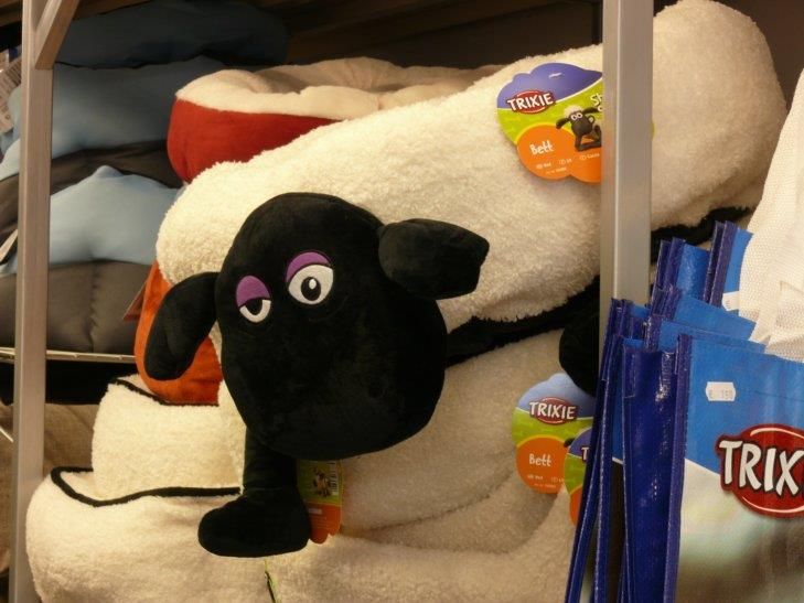 Eine Ausstellung von Stofftieren, darunter ein schwarzes Schaf und eine Trixie-Tasche