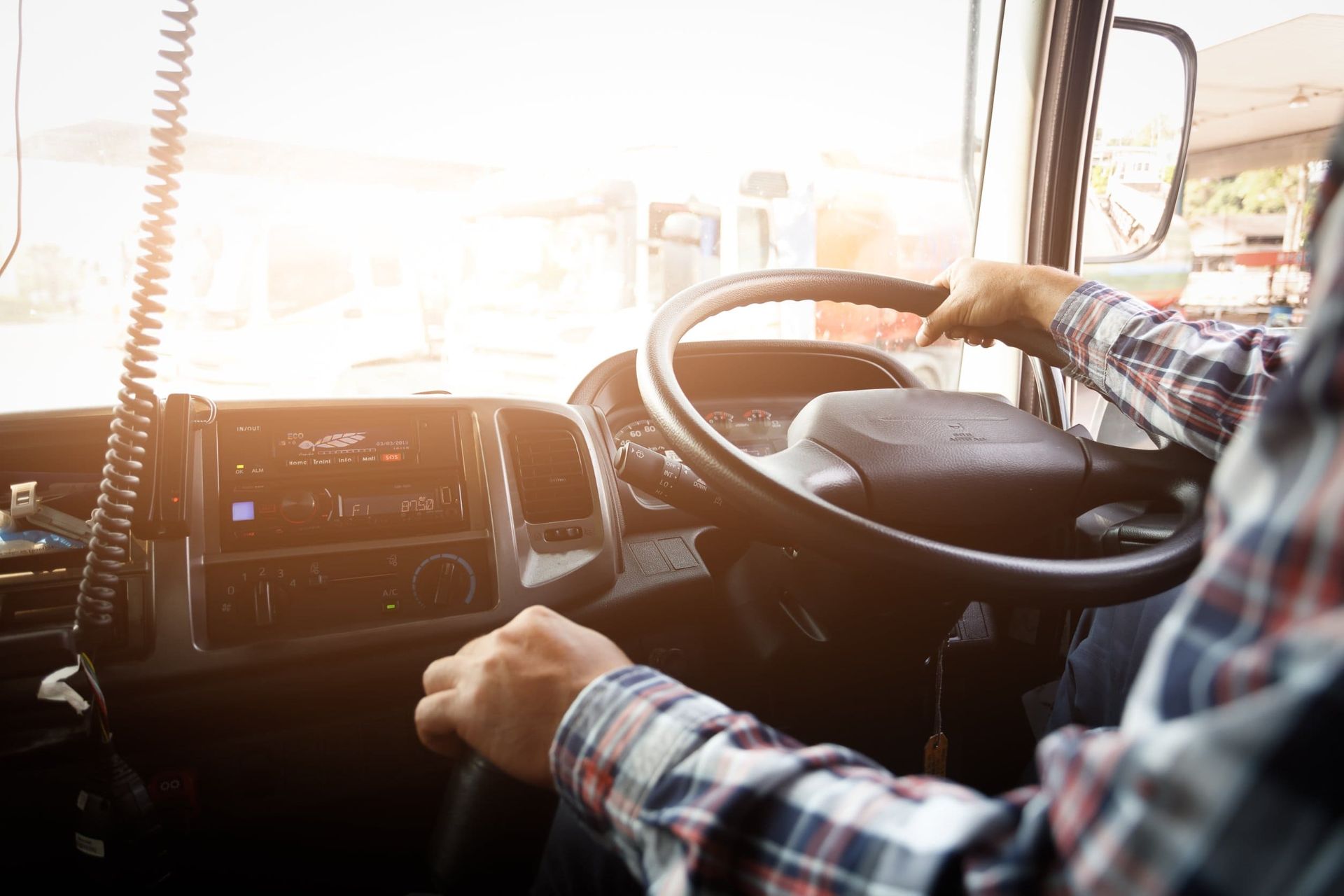 Un hombre conduce un camión con las manos en el volante.