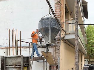 Un trabajador de la construcción está vertiendo hormigón en un cubo.