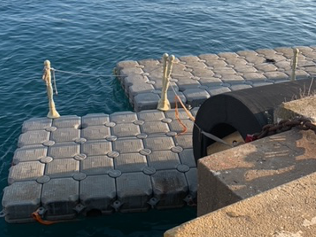 Un muelle flotante en el agua junto a un muro de hormigón.
