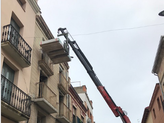 Una grúa está levantando un balcón en la parte superior de un edificio.