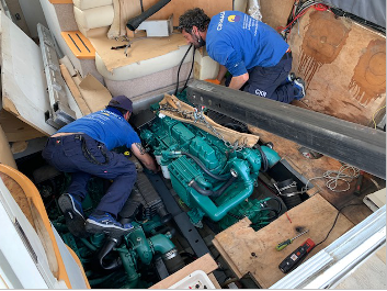 Dos hombres están trabajando en el motor de un barco.