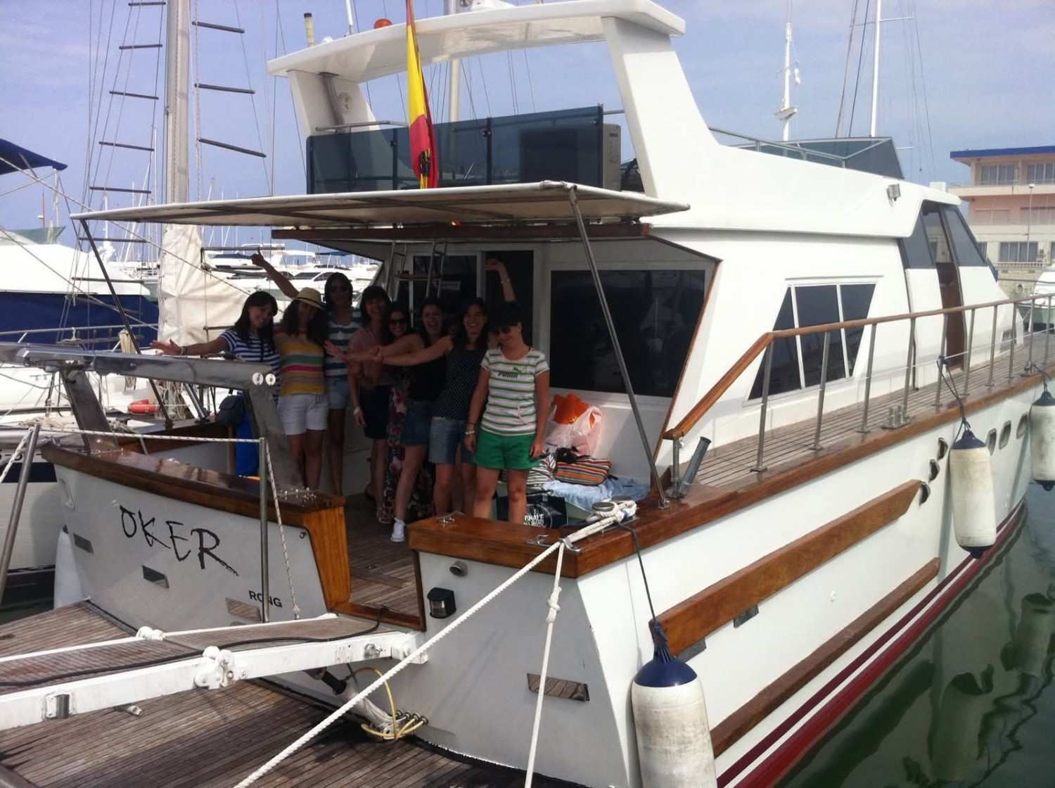 A group of people standing on the deck of a docked white yacht, with the boat's name