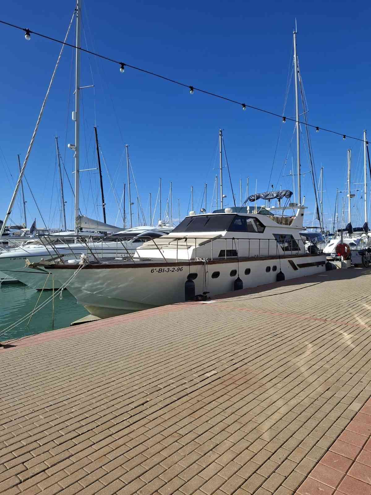 A white motor yacht docked at a marina on a sunny day with a clear blue sky.