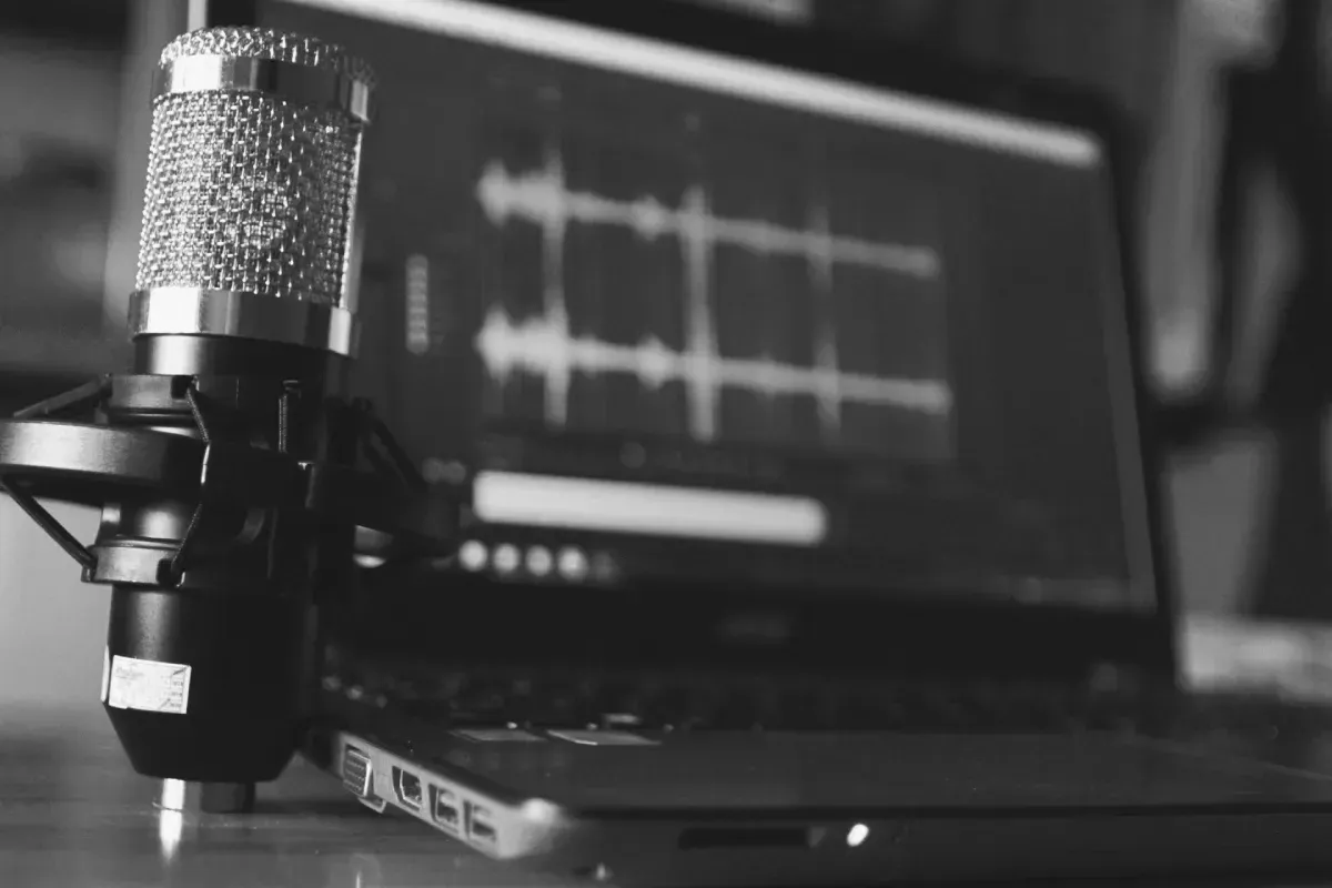 Un micrófono de condensador se encuentra frente a una computadora portátil que muestra una forma de onda de audio