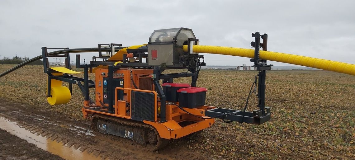 Machine de travaux publics orange au travail dans un champ 