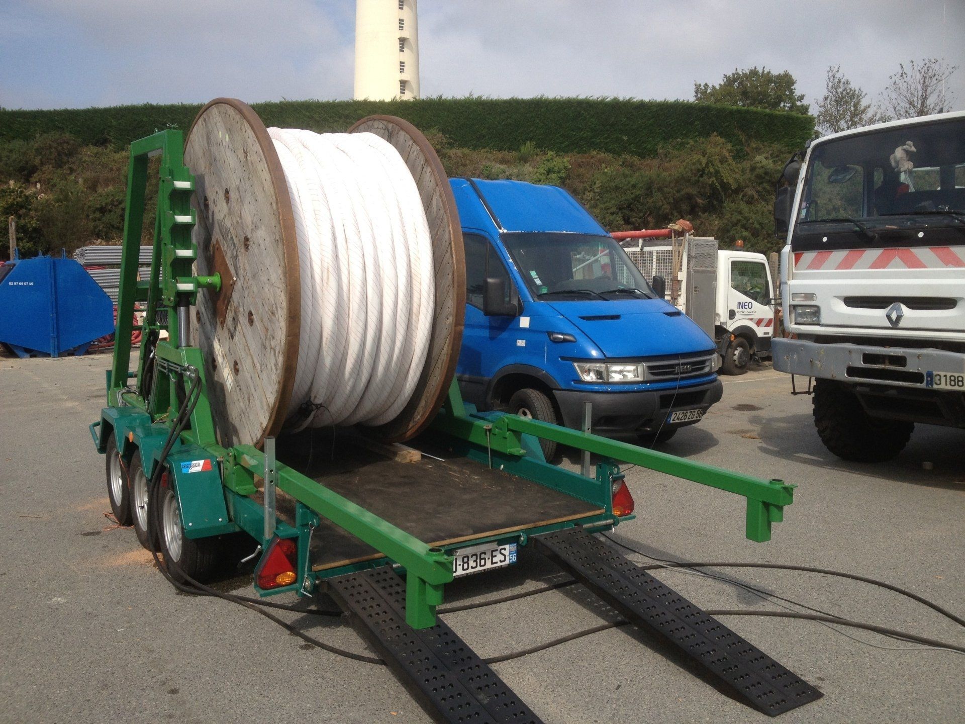 Rouleau de géotextile blanc sur remorque verte 