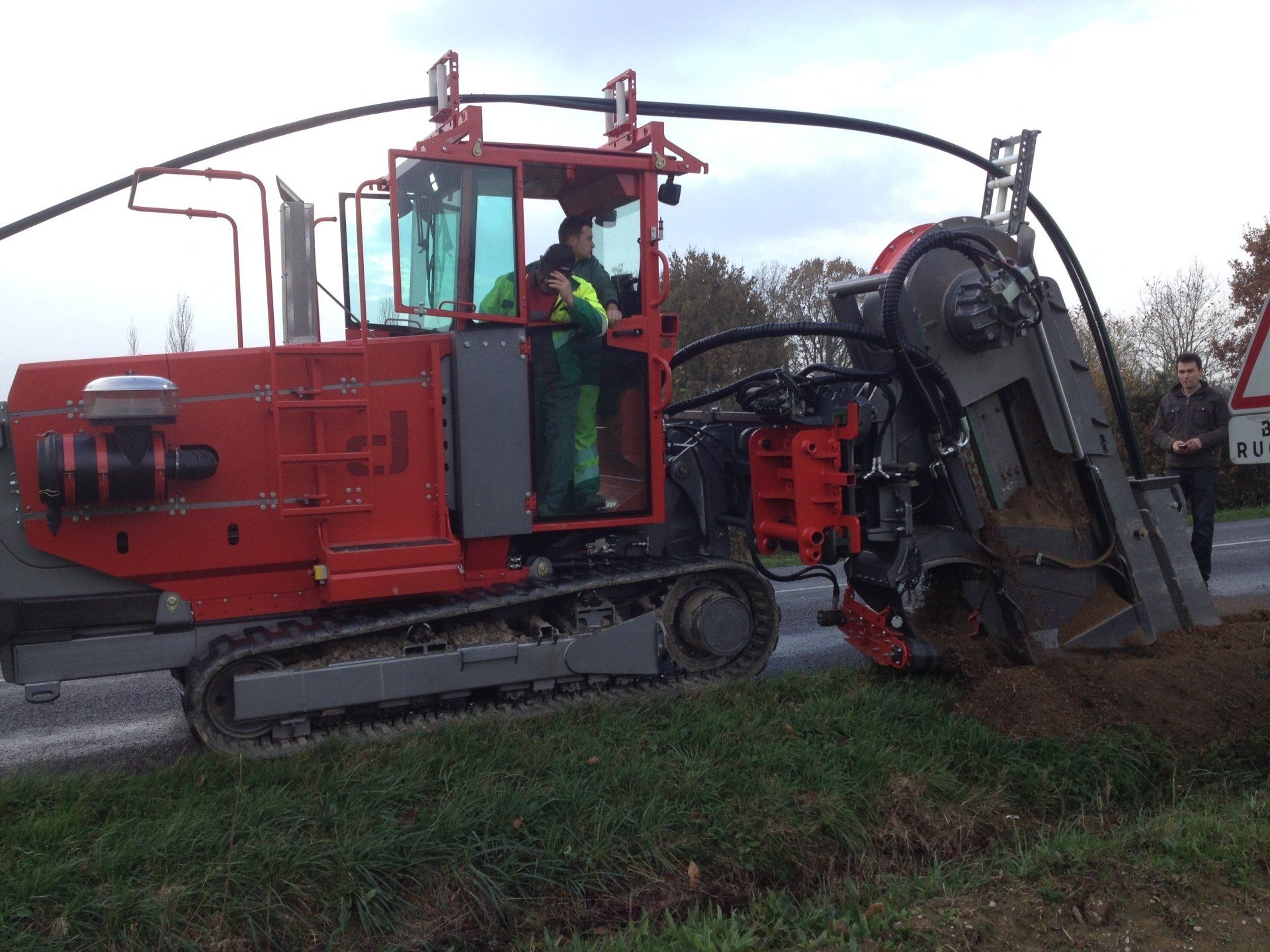 Trancheuse rouge en cours d'utilisation au bord d'une route